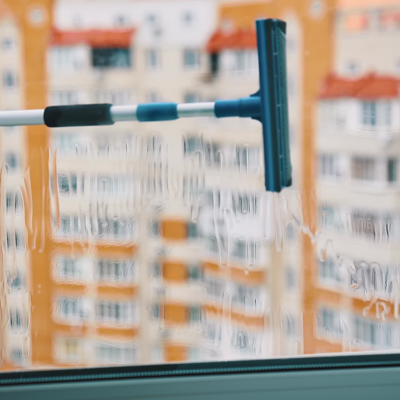 Wiping window with a brush. View from flat on a plastic window cleaning with a special tool in the city. Housekeeping concept