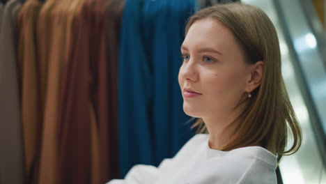 primer plano de una mujer mirando la ropa en los estantes con una cálida sonrisa mira hacia otro lado, emanando felicidad y satisfacción en una tienda brillante y bien iluminada, con una iluminación suave que destaca su cara y su ropa