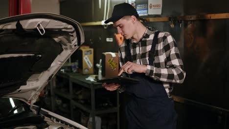 Mechanic-inspects-the-car-undercarriage-way-with-a-digital-tablet