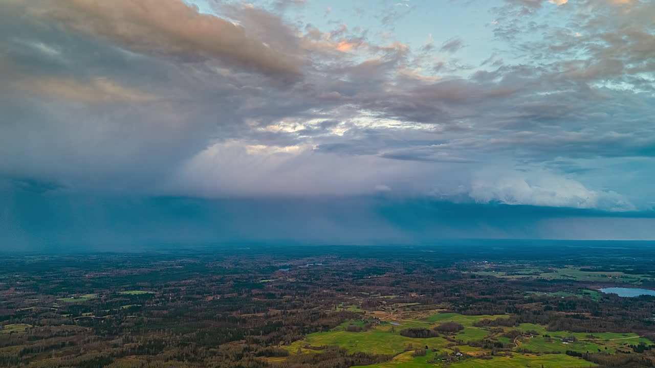 Rainstorm with dramatic cloudscape over a rural landscape - high altitude aerial time lapse
