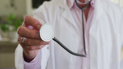 sección media de un médico masculino caucásico con un estetoscopio en casa