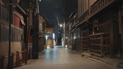 a dimly lit alley in kyoto at night, lined with traditional buildings and glowing lanterns, creates a moody and atmospheric scene in the historic city.