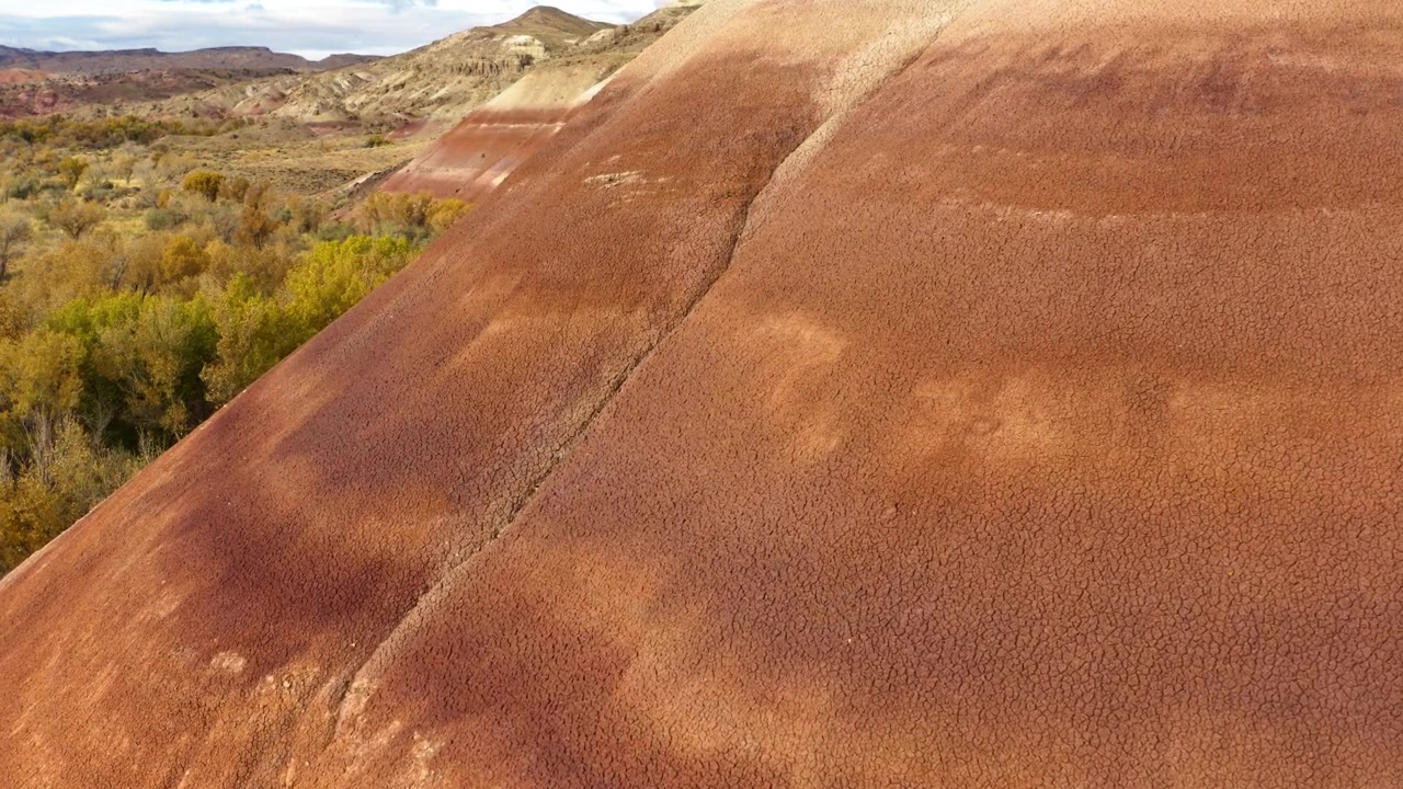 Close-up aerial view of the textured, reddish slope of a Bentonite Hill with visible erosion patterns. Southern Utah, USA