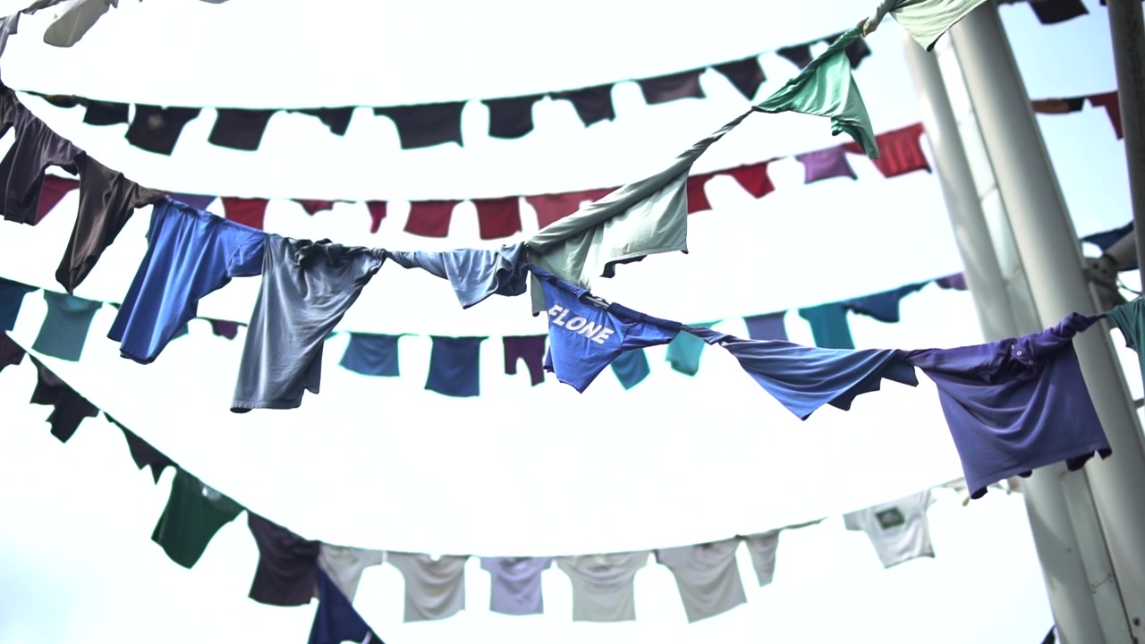 Clothing Lines hanging outdoors full of multicolored clothes.
