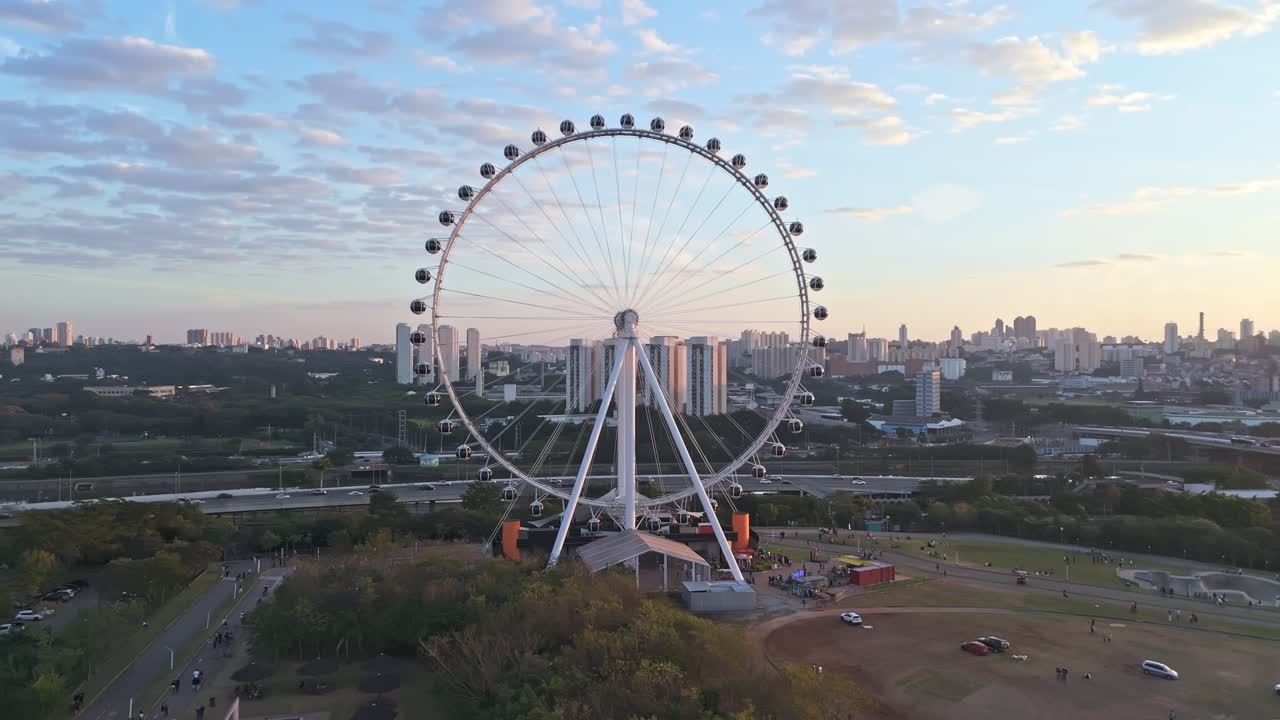 Orbital aerial view of cantilever observation wheel a sunny day before sunset in Saint Paul, Brazil. Clear Sky, Buildings landscape. Roda Rico.