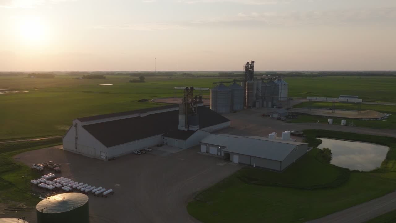 Planta de fertilizantes con silos de grano cilíndricos durante el atardecer en la granja. Toma aérea
