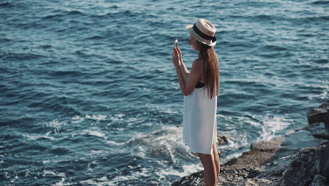 woman taking picture on a cliff by the ocean