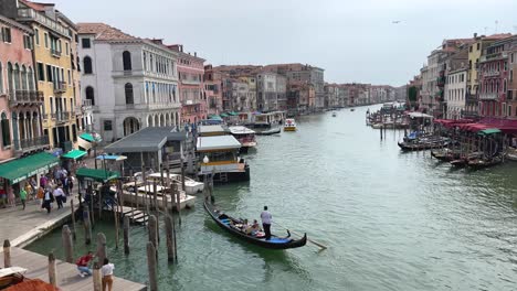 view from rialto bridge, gondolier steering gondola to pier on grand canal in venice, italy