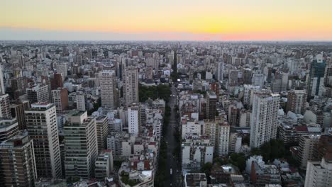 dolly in flying over long avenue at sunset in the middle of busy belgrano neighborhood, buenos aires, argentina