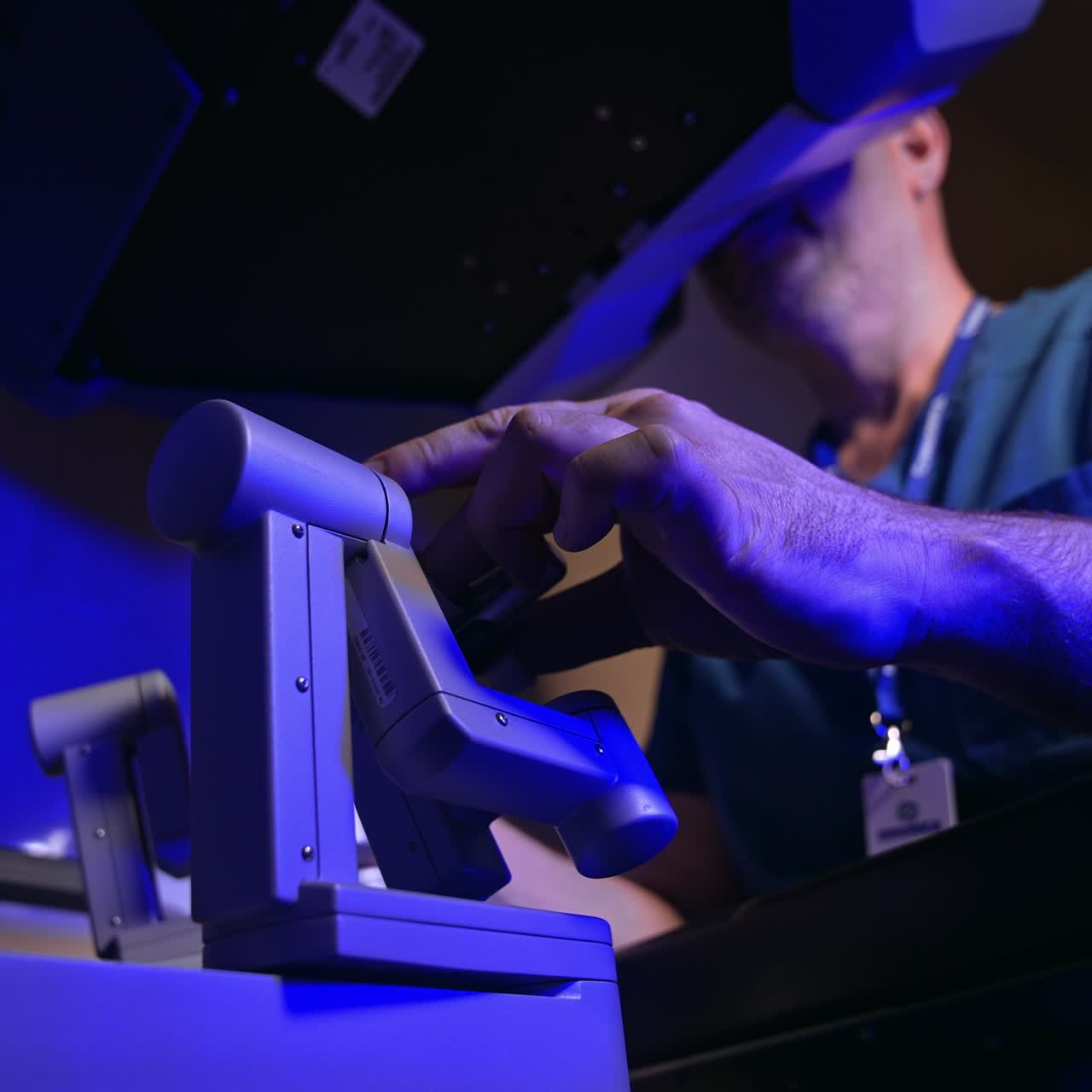 Professional surgeon sitting and operating robotic medical equipment. Doctor looks at special device and moves the handles. Low angle view