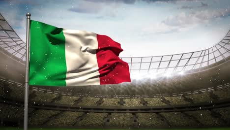 Animation-of-camera-flashes-and-white-particles-over-waving-italy-flag-against-sports-stadium