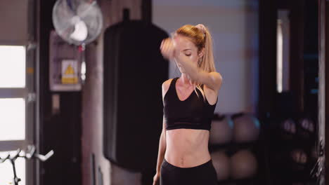 Attractive-Young-Female-Athlete-Doing-Warm-Up-Exercise-At-Fitness-Centre