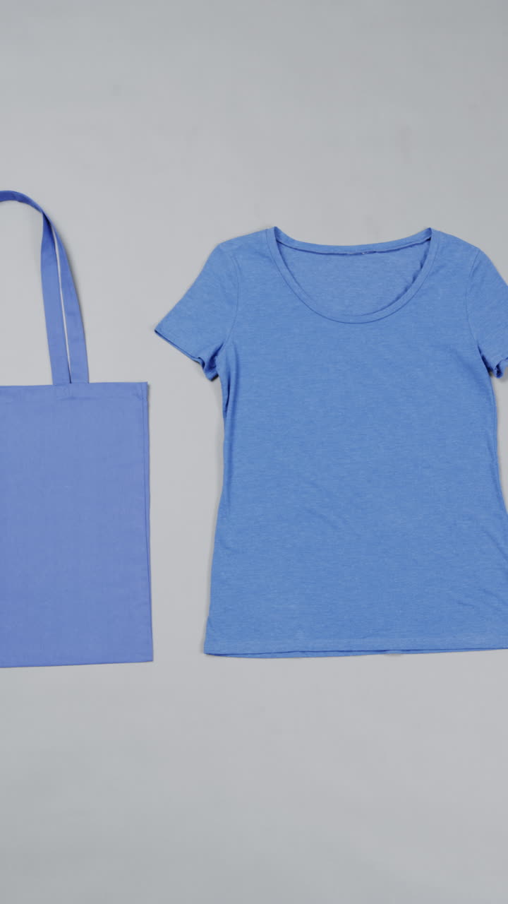 Video verticale di una borsa di tela blu e una t-shirt con spazio per il testo su sfondo bianco