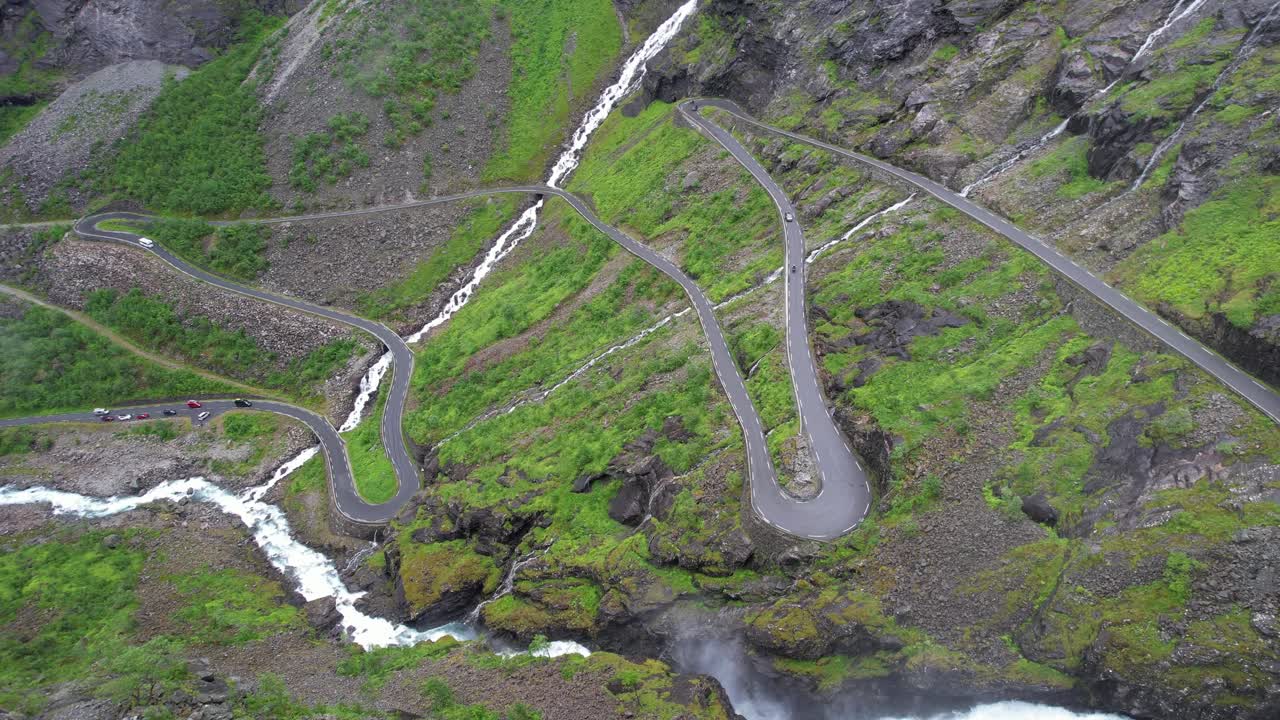 la cascada de montaña se derrama sobre los coches en el camino de los trolls