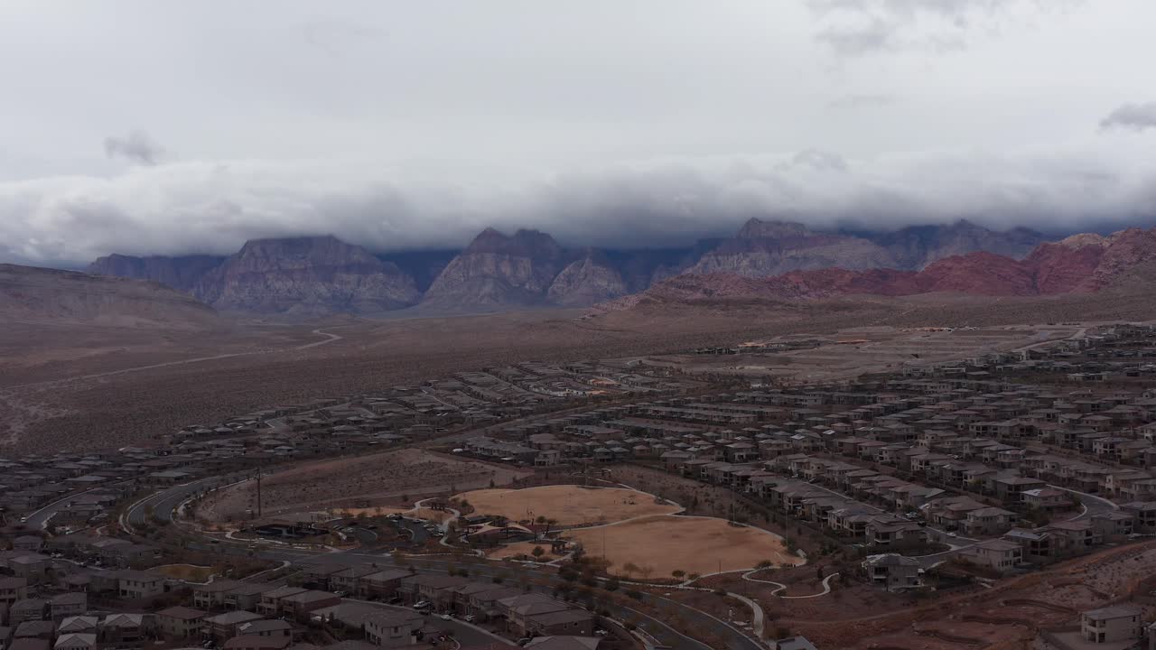 Ampia ripresa aerea in discesa di Red Rock Canyon con sobborghi desertici in primo piano a Las Vegas, Nevada