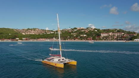 Antigua-and-Barbuda---2023:-aerial-establishing-shot-of-Wadadli-cats-catamaran-boat-ride-on-turquoise-open-ocean-waters,-caribbean-cruise-tour