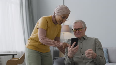 mujer árabe enseñando a un anciano a usar un teléfono inteligente