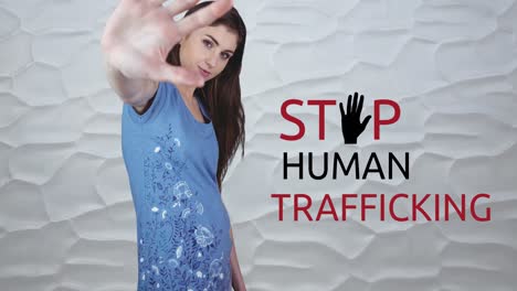 Animation-of-stop-human-trafficking-text-over-caucasian-woman-with-stop-gesture