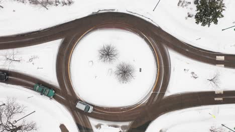 aerial top down, traffic driving around small roundabout during winter