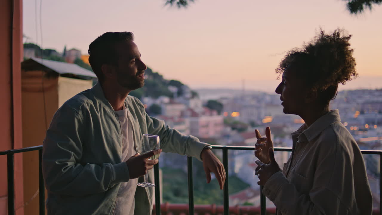 Primo piano di una coppia felice che parla in un punto panoramico al tramonto. Amici che conversano su una terrazza con ringhiera.