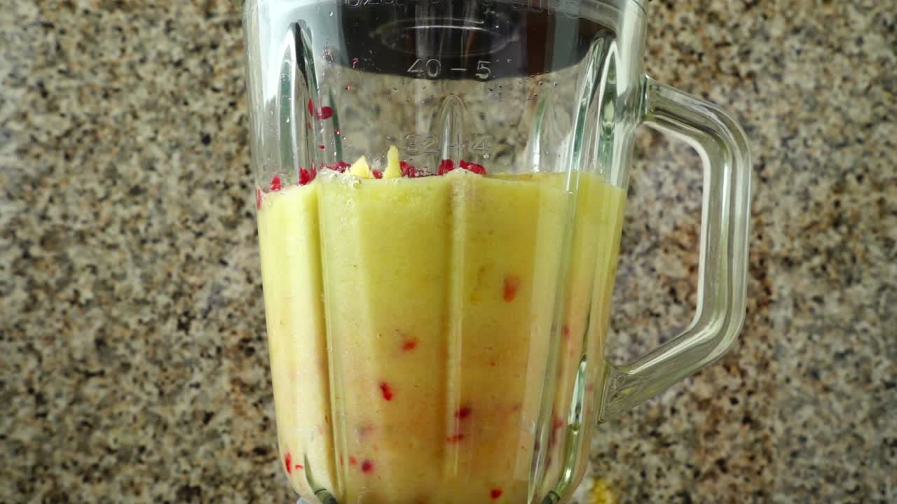 Cocktail di pere, mele, uva, lamponi, banane e succo d'arancia. Movimento rallentato.