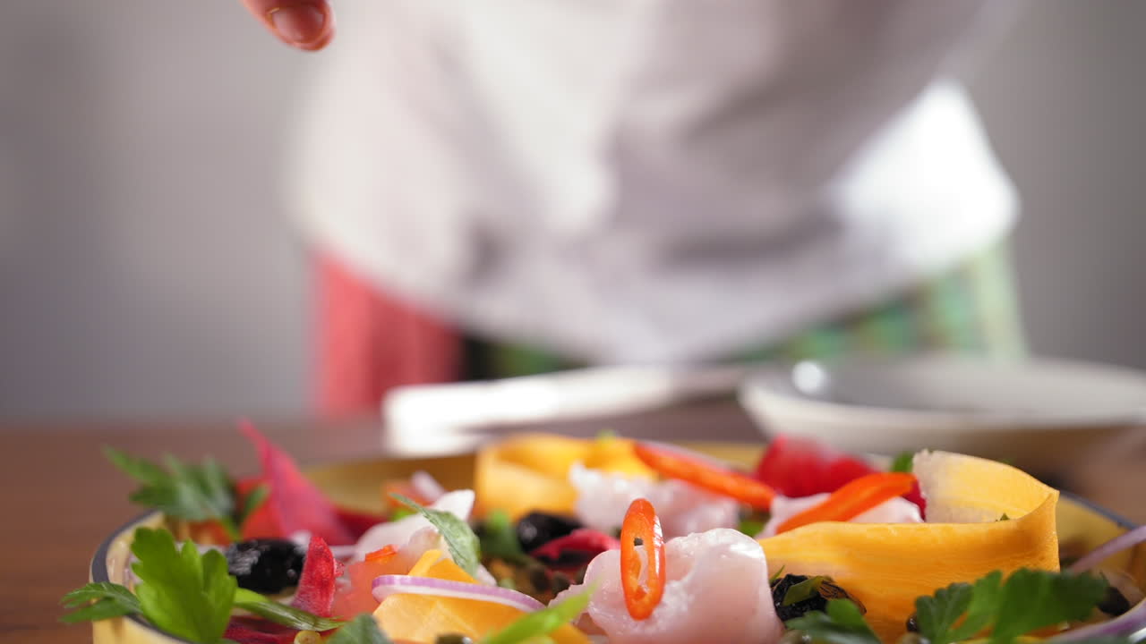 el chef con una camisa blanca prepara un carpaccio de lubina y le pone capparis -empuje en cámara lenta para enfocar la toma