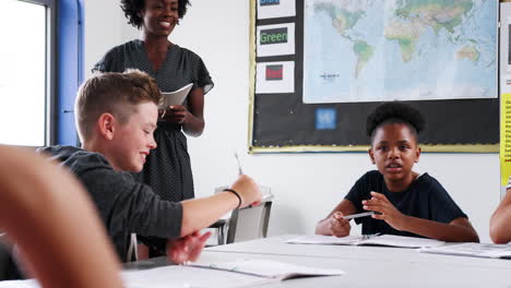 Weibliche-Gymnasiallehrer,-Die-Eine-Gruppe-Von-Schülern-Unterrichten,-Die-Im-Klassenzimmer-Am-Tisch-Arbeiten