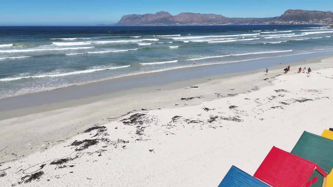 Aerial drone view of colorful beach huts on white sandy shore, vibrant seaside scenery with turquoise ocean and summer holiday atmosphere South Africa