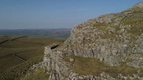 Slow-Aerial-Drone-Shot-Flying-Past-Warrendale-Knots-revealing-Settle-and-Giggleswick-Town-Yorkshire-Dales-Countryside-Grass-and-Rocky-Hills-with-Dry-Stone-Walls-on-Sunny-Summer-Day-UK