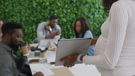 african-american-business-people-meeting-pregnant-team-leader-woman-using-tablet-computer-presenting-mobile-application-design-sharing-creative-ideas-for-communication-app-in-office-presentation
