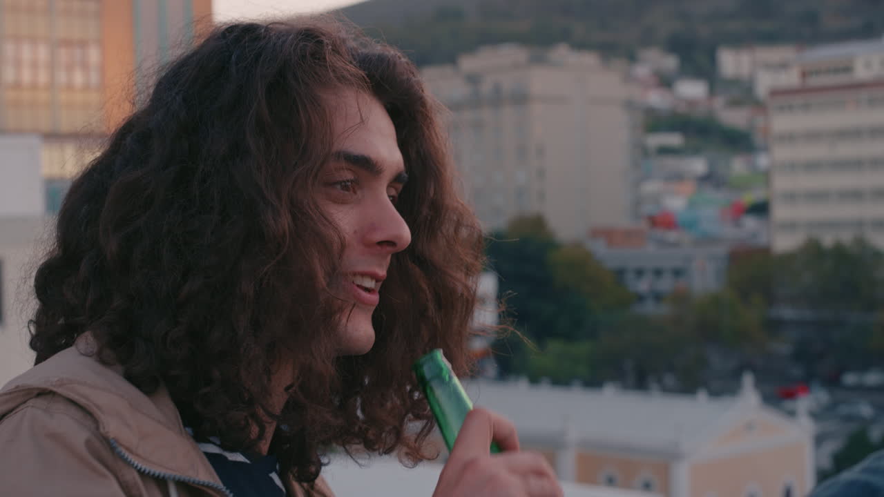 옥상에서 행복한 친구들이 대화를 나누고, 우정을 즐기고, 재회하고, 술을 마시고, 신선한 맥주를 마시고, 해가 지는 도시의 전망을 공유하고