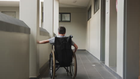 navigating school hallway, student in wheelchair with backpack moving forward