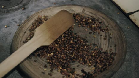 Zeitlupenaufnahmen-Eines-Paddels,-Das-Kochende-Kaffeebohnen-Auf-Einem-Heißen-Stein-Auf-Einem-Ofen-Bewegt