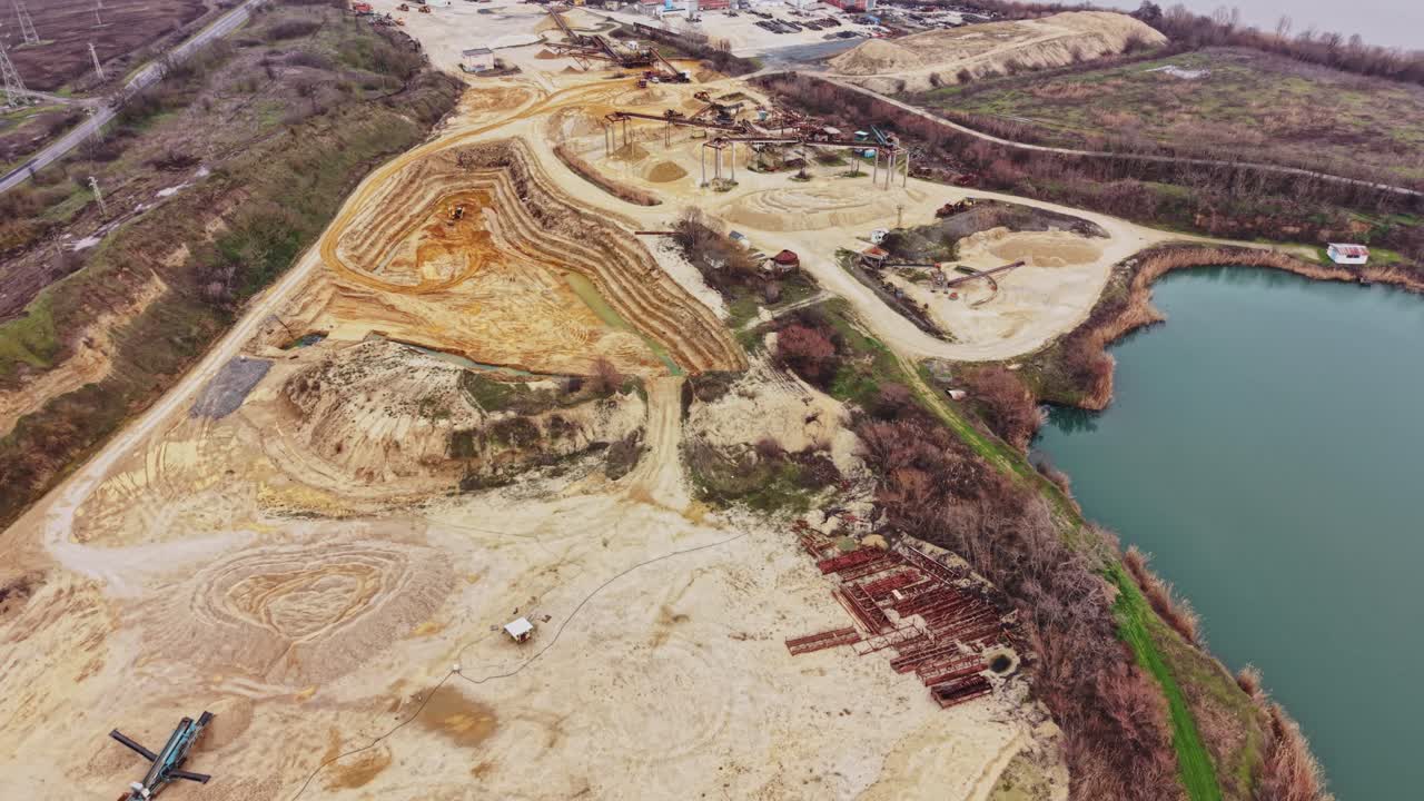 Sand quarry area with water body showing extraction and vegetation