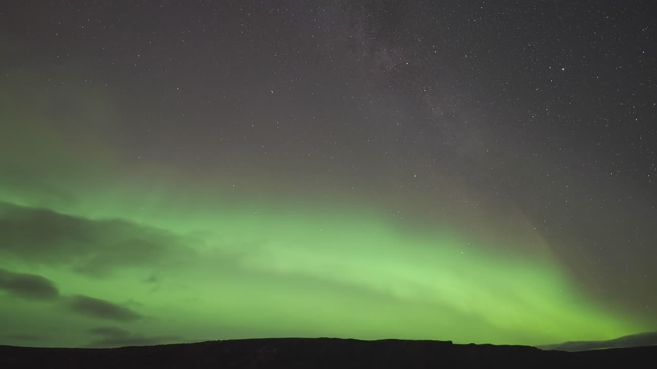 un video de lapso de tiempo que captura la impresionante aurora boreal iluminando las aguas tranquilas de un fiordo en una oscura noche de invierno