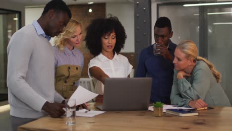 diverse group of business colleagues talking in a meeting room using laptop