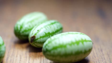 raw fresh tiny green mexican cucamelon placed on wooden kitchen surface selective focus dolly left