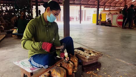 woman is carving the design on wood for temple in thailand