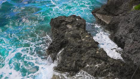 Tagsüber-Ist-Das-Tiefblaue-Wasser-Sichtbar,-Wenn-Es-Gegen-Die-Felsige-Küste-Prallt,-Die-Weißen-Schaumkronen-Und-Die-Gischt,-Die-Durch-Den-Aufprall-Entstehen,-Sind-Eine-Atemberaubende-Visuelle-Darstellung-Der-Kraft-Und-Stärke-Des-Ozeans