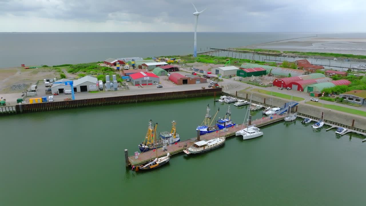 Top down view backward aerial overlooking moored boats at Borkum island harbor