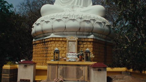 Panorama-of-a-large-Buddha-statue-sitting,-surrounded-by-trees