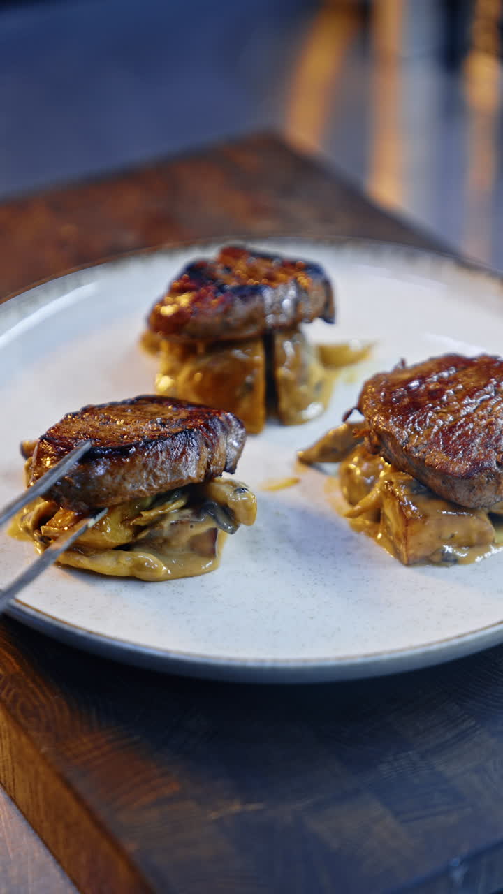 Chops of fried meat are placed on the vegetables. Serving the dish of steaks and potatoes. Close up. Vertical video.