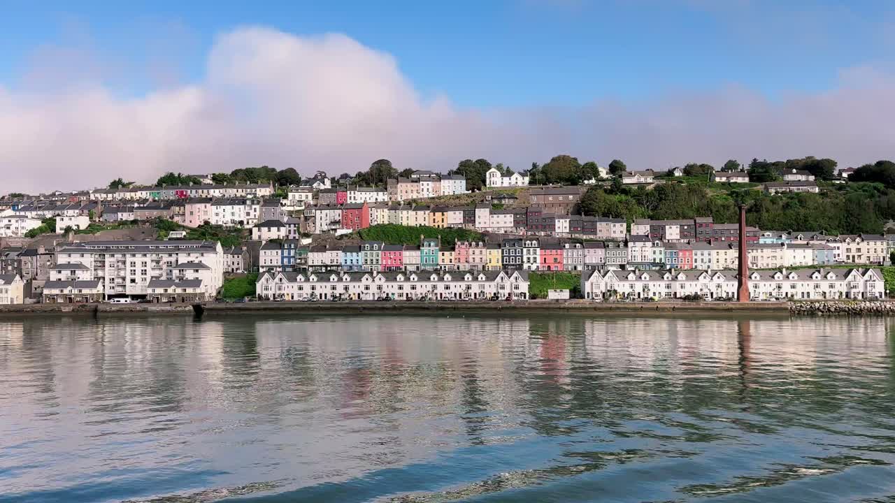día soleado sobre el panorama de cobh, una vista desde el agua con hilera de casas, cielo azul, catedral