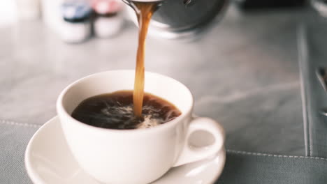 Close-up-shot-of-a-woman's-hand-pouring-hot-coffee-from-French-press-into-coffee-cup