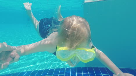 the girl is learning to dive in the pool she holds his father's hand she wears a mask for scuba divi