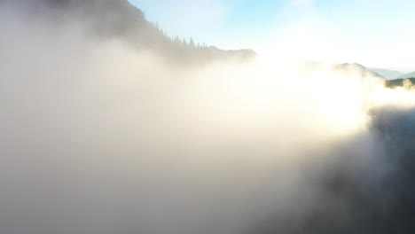 flying into low clouds in mountain valley under golden hour sunlight on summer