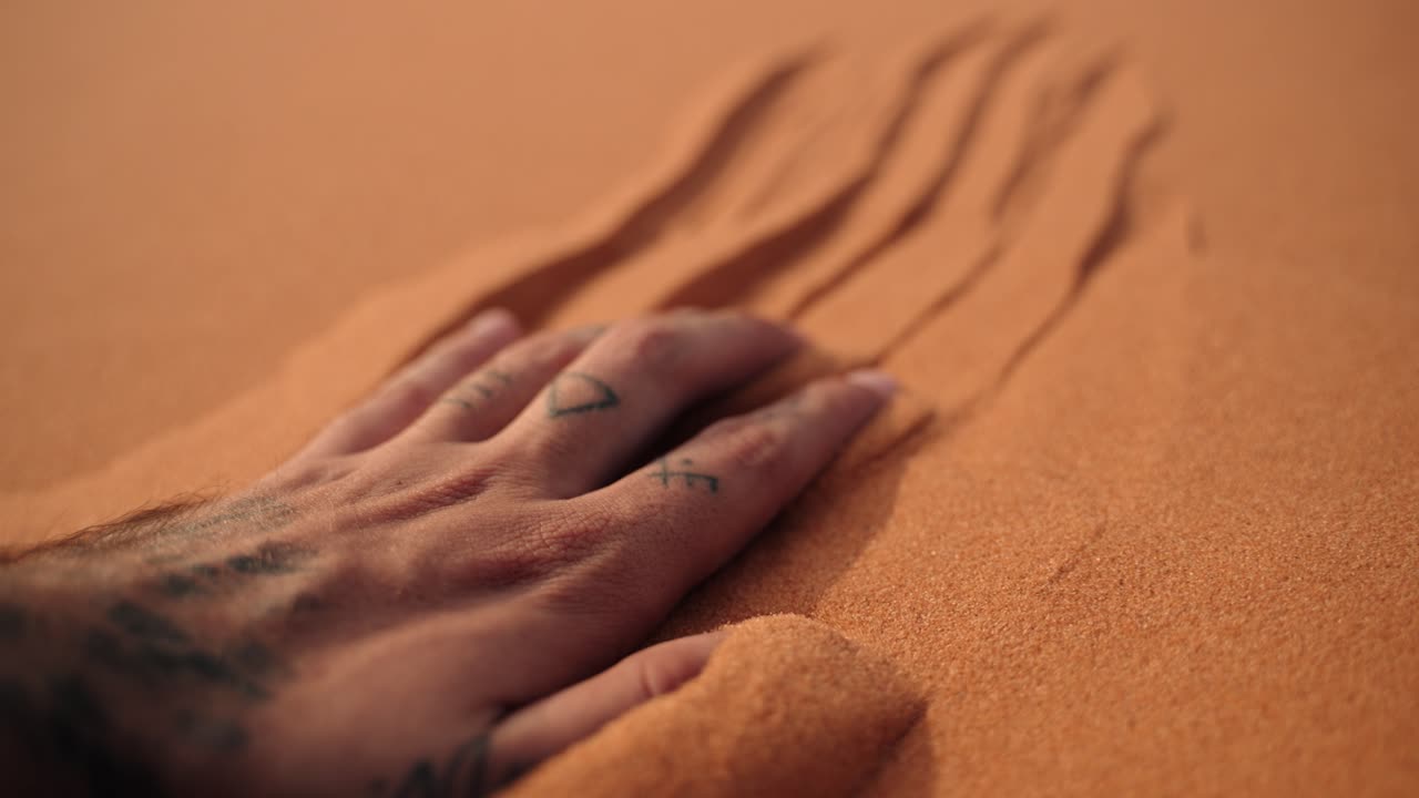 Hand touching and sliding across soft Sahara desert sand Morocco