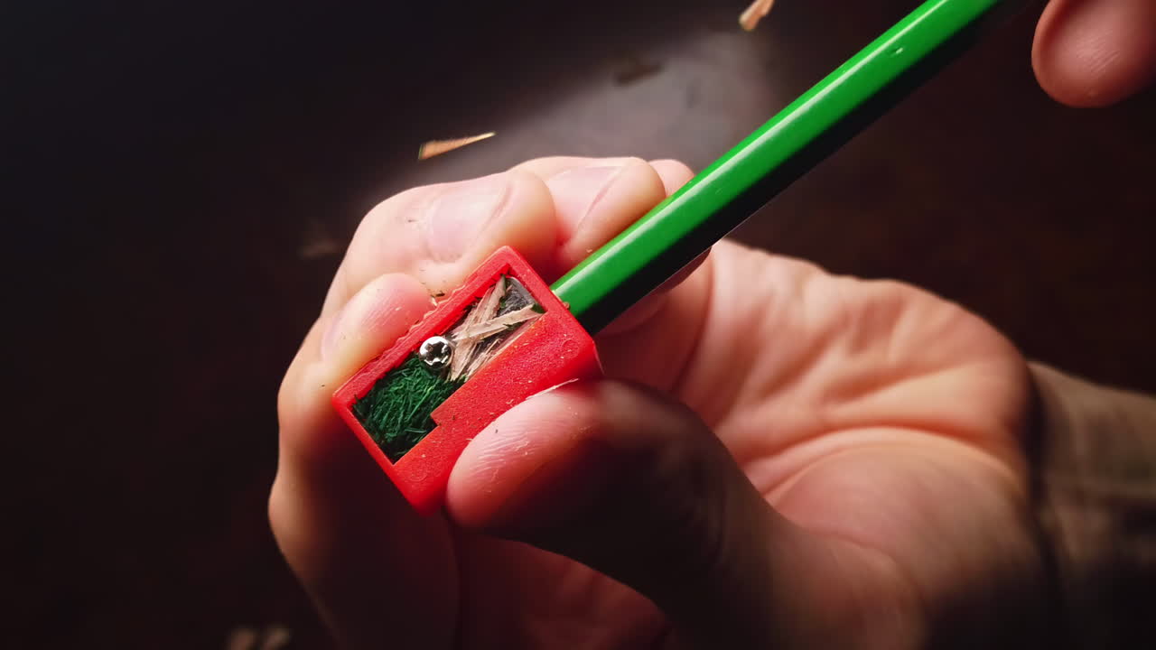 Overhead slow motion of sharpening the pencil in sharpeners on top of the wooden table