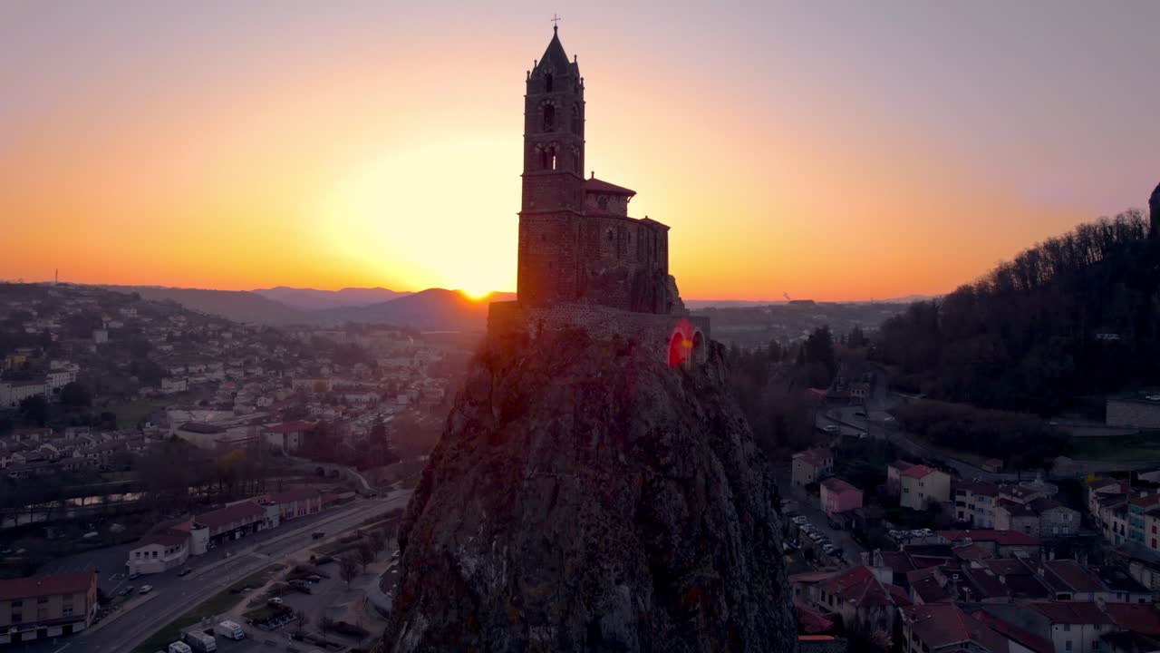 aerail shot revealing the Saint Michel d'Aiguilhe rock and chapel at sunrise in le Puy en Velay, haute loire department, auvergne rhone alpes region, france