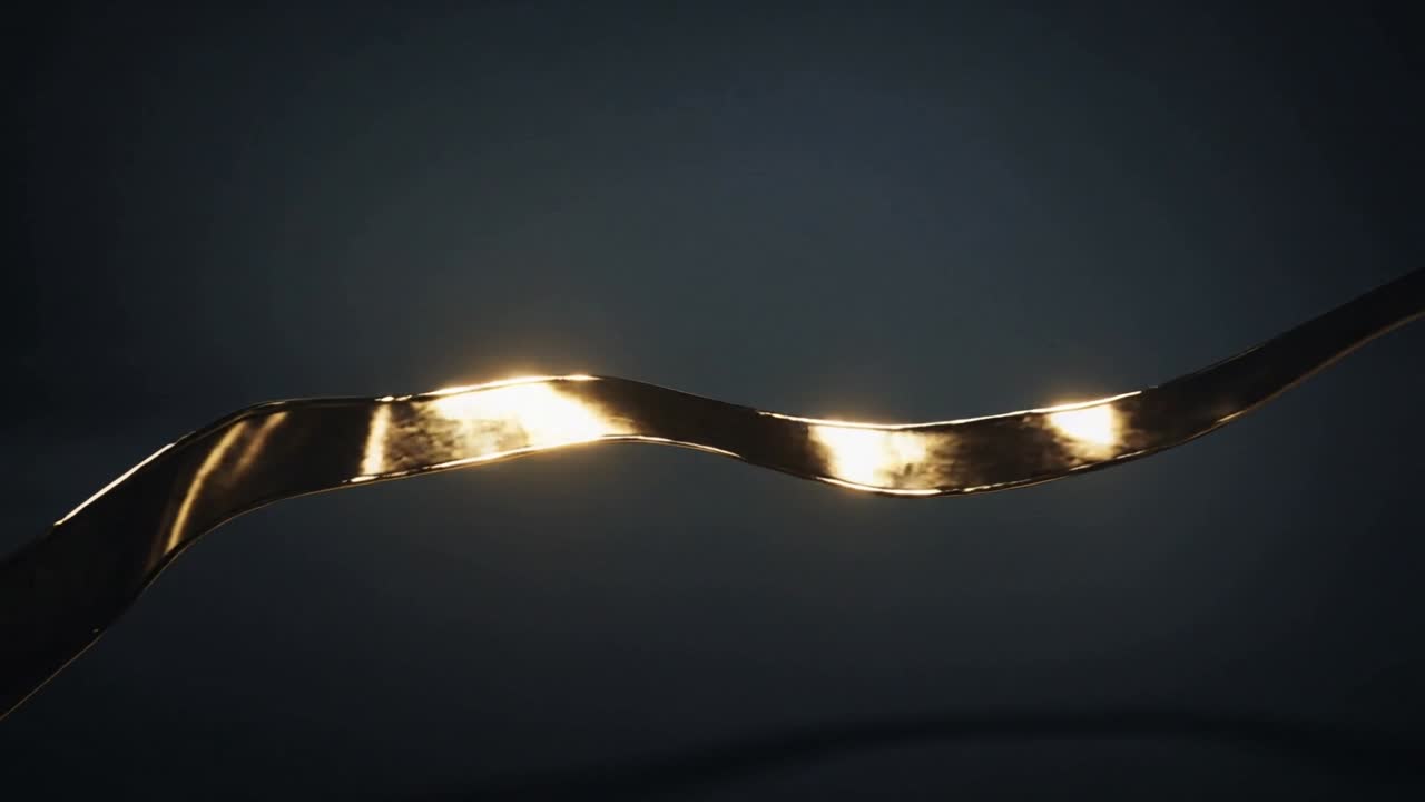 Nastro metallico che si attorciglia su sfondo scuro, con luci da studio che creano riflessi per il design.